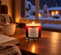 Velvet Roast candle by a snowy window with hot chocolate and Christmas lights