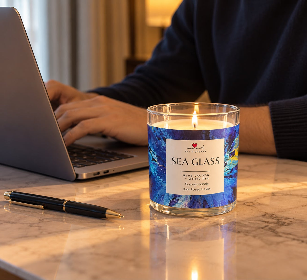 Sea Glass candle by Art N Dreams on a marble desk beside a laptop